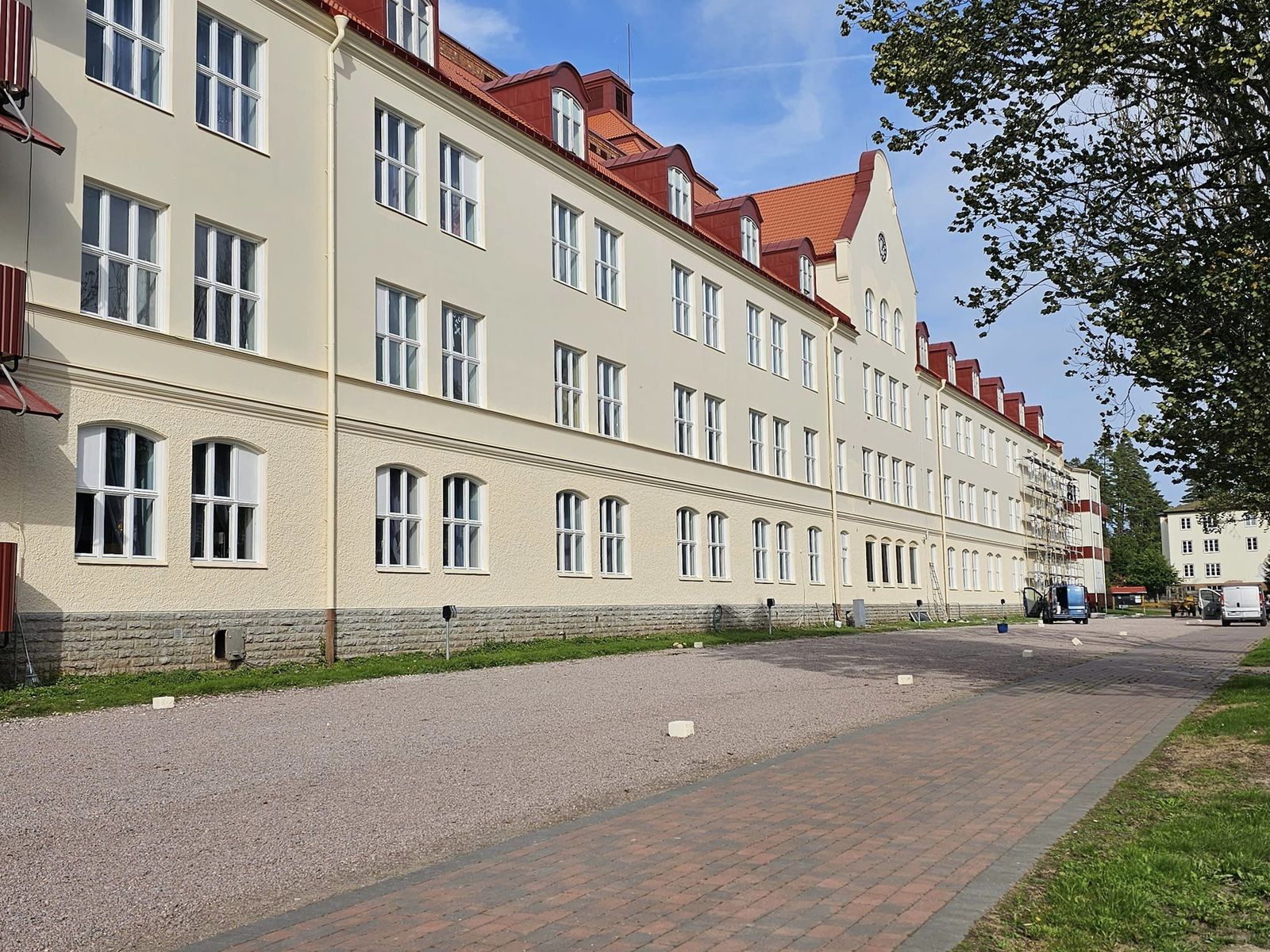 Stora Ekebergs långa, ljusa sanatoriebyggnad med rött tegeltak och klockgavel en solig dag